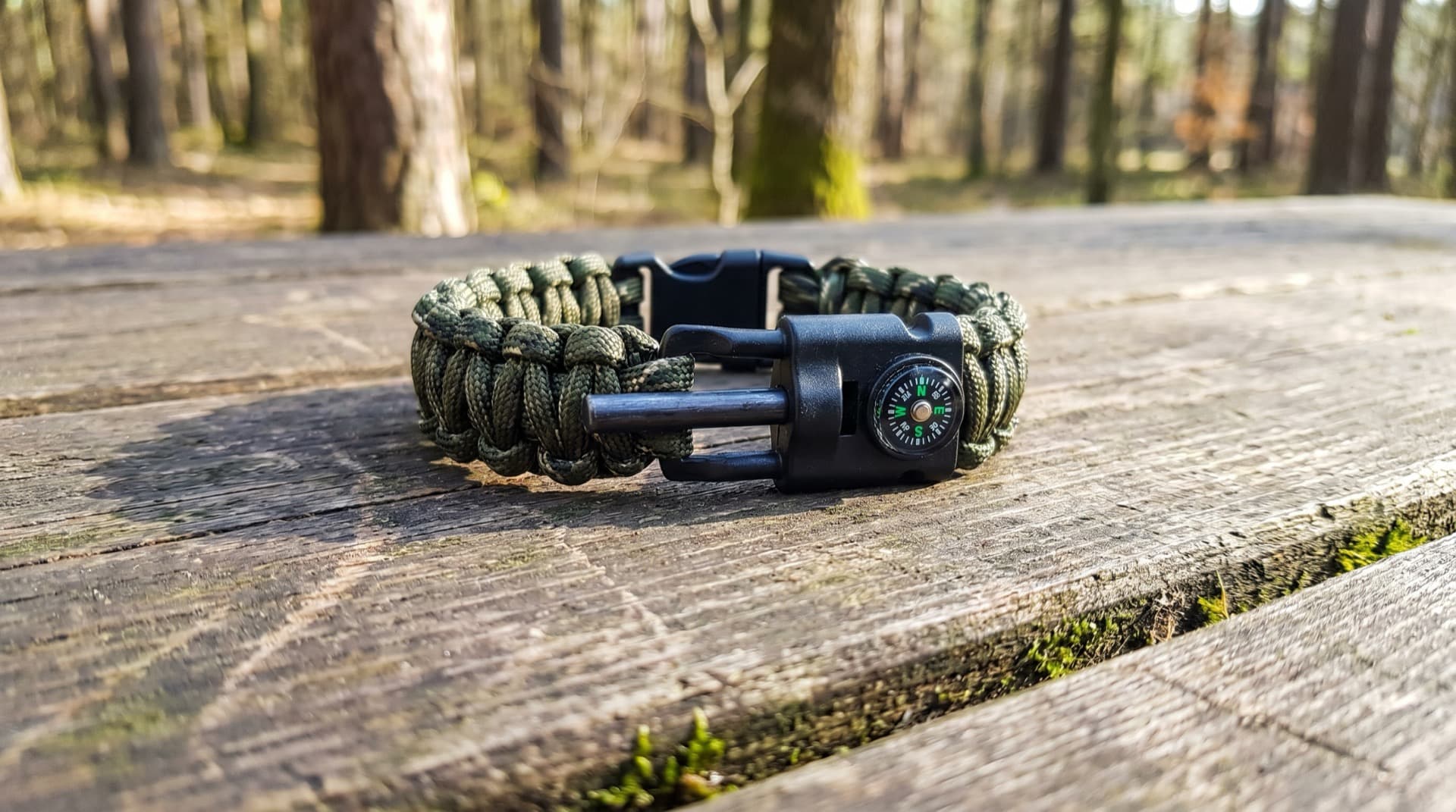 Complete paracord bracelet on wooden surface in deep forest background