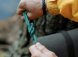 Customer tying a teal paracord knot outdoors