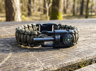 Camo paracord survival bracelet with compass on a log